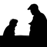 About High contrast silhouette photo capturing two adults conversing against a white background.